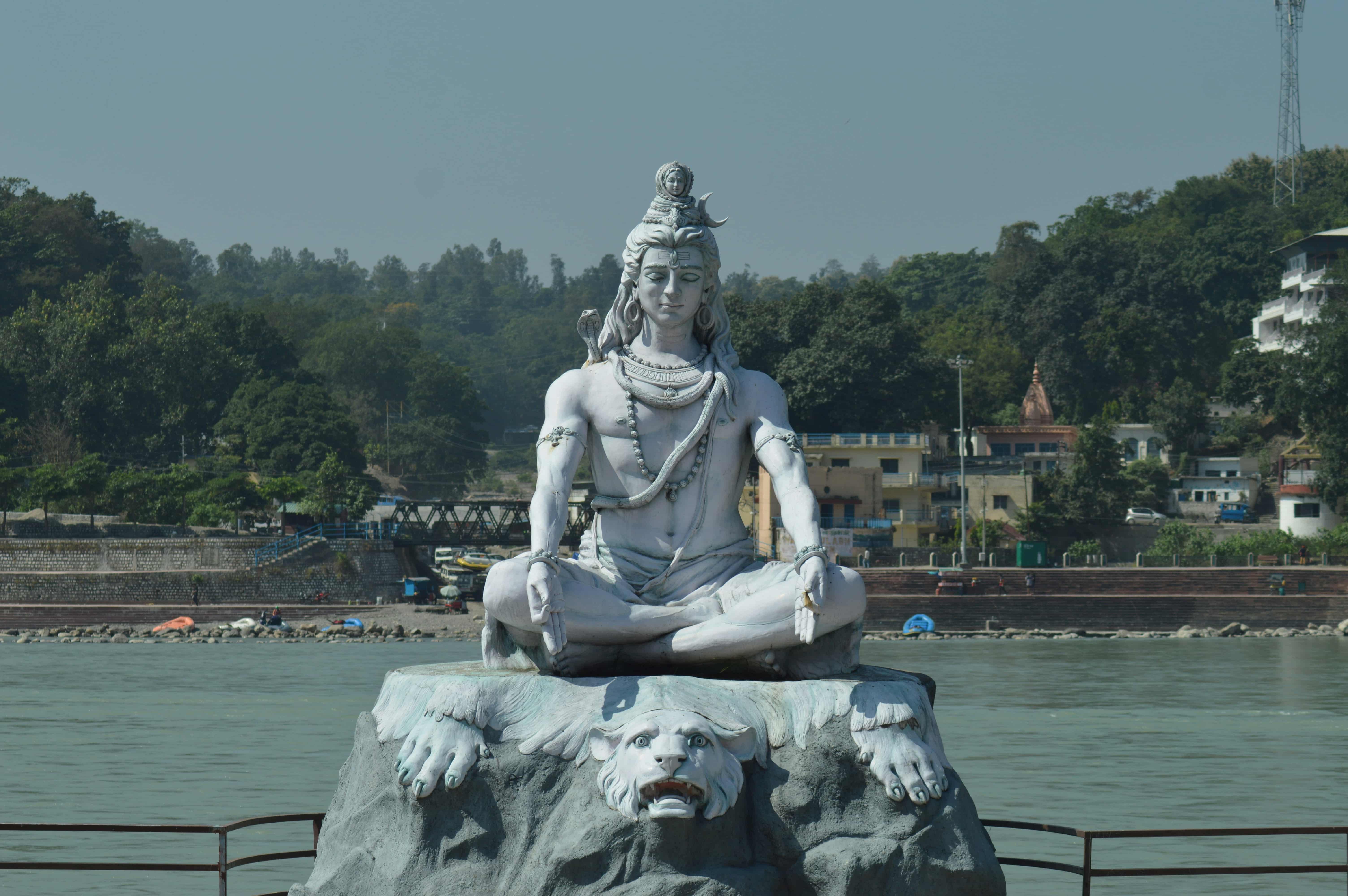 A statue of Shiva seated in meditation beside the Ganga
